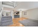Bright living room features hardwood floors, staircase, and seamless open floor plan to kitchen with breakfast bar at 613 Rio Rancho Way, Brighton, CO 80601
