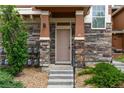 Charming front entrance with stone accents, a small porch, and well-maintained landscaping at 7130 Simms St # 206, Arvada, CO 80004