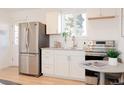 Modern kitchen features stainless steel refrigerator, white cabinets and breakfast table at 3903 W Nevada Pl, Denver, CO 80219