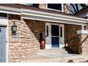 Inviting entryway featuring stone accents, a covered porch, and a stylish front door at 1625 Adobe Pl, Highlands Ranch, CO 80126