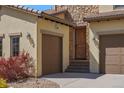 Charming home exterior featuring a three-car garage, stone accents, and a beautifully stained wooden door at 15179 W Washburn Ave, Lakewood, CO 80228