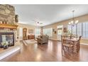 Spacious room featuring a stone fireplace, plantation shutters, hardwood flooring, and adjoining dining area at 6761 Mary Ct, Castle Pines, CO 80108