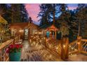 Cabin exterior featuring a wooden deck with decorative railings and string lights at twilight at 30264 Upper Bear Creek Rd, Evergreen, CO 80439