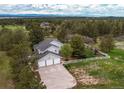 Expansive aerial view of the property showcasing a large lot, mature trees, and mountain views at 10393 Deerfield Rd, Franktown, CO 80116