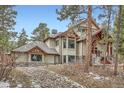 View of a residence with architectural details, featuring timber accents, and a landscaped exterior with natural rock features at 1662 Gore Dr, Larkspur, CO 80118