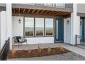 Inviting covered porch featuring an outdoor chair, contemporary lighting, and a stylish front door at 3109 W Bates Ave, Denver, CO 80236