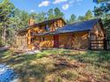 Charming exterior featuring wood siding, a vibrant red front door, and a lush green lawn, blending nature and home at 18680 Arrowwood Dr, Monument, CO 80132