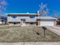 Charming split-level home with a well-maintained lawn and a brick accent facade at 7449 W Fremont Ave, Littleton, CO 80228