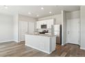 Bright kitchen featuring an island with a sink, stainless steel appliances, and white cabinetry at 48285 Shetland Dr, Bennett, CO 80102