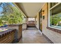 Spacious covered porch with brick railing, concrete flooring, and a hanging swing for relaxing at 810 Adams St, Denver, CO 80206