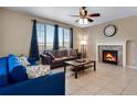 Inviting living room with a fireplace, ceiling fan and two couches with large windows at 17035 E 102Nd Pl, Commerce City, CO 80022