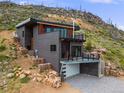 Striking exterior with a modern design, stone accents, and a second-story balcony overlooking a scenic landscape at 718 Emerson Gulch Rd, Boulder, CO 80302