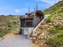 Modern home exterior featuring a flat roof, brick and wood facade, balconies, and concrete stairs on a hillside at 718 Emerson Gulch Rd, Boulder, CO 80302