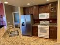 Bright kitchen features granite countertops, stainless steel refrigerator and white gas range at 15346 Heritage Cir, Thornton, CO 80602