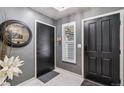 Home's entry way featuring dark doors, a round mirror, decorative flowers, and marble tile flooring at 5300 Tabor St, Arvada, CO 80002