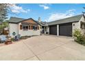 Home's exterior view showcasing the three-car garage, large driveway and well-kept garden with lawn furniture at 5300 Tabor St, Arvada, CO 80002