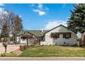 This charming home's front yard with green grass, garden beds, mature trees, and large driveway at 5300 Tabor St, Arvada, CO 80002