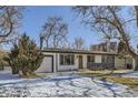 Single-story home with an attached garage, contrasted by the snow-covered yard and bare trees at 2582 S Birch St, Denver, CO 80222