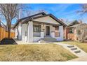 Stylish painted brick home featuring a covered porch with black trim and a well-kept lawn at 1317 Monroe St, Denver, CO 80206