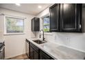 Stylish kitchen with sleek black cabinets, stainless steel sink and modern fixtures beneath a large window at 8035 W Eastman Pl # 106, Lakewood, CO 80227