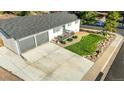 Aerial view of a single story home featuring a large driveway, attached garage, landscaped yard, and street view at 7100 Saulsbury St, Arvada, CO 80003