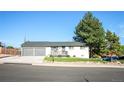 Well-maintained single-story house featuring a gray roof, attached garage, small porch, and beautiful tree at 7100 Saulsbury St, Arvada, CO 80003