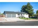 Well-maintained single-story house featuring a gray roof, attached garage, small porch, and beautiful tree at 7100 Saulsbury St, Arvada, CO 80003