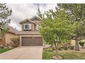 Charming exterior showcasing a two-car garage, stone accents, and lush landscaping at 9825 S Iris Ct, Littleton, CO 80127