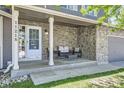 Inviting front porch with stone accent wall and seating area with cushions, creating a cozy outdoor space at 11218 Newark Ct, Commerce City, CO 80640