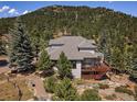 Beautiful exterior boasts large deck and a well-maintained garden, set against a backdrop of lush trees at 31518 Niakwa Rd, Evergreen, CO 80439