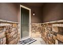 Front porch with stone walls, a dark green door and a 'Home Sweet Home' doormat at 10397 Helsinki St, Parker, CO 80134