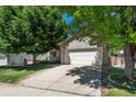 A charming home with a brick facade and a two-car garage, surrounded by mature trees and lush greenery at 5332 S Lisbon Way, Centennial, CO 80015