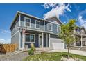 Inviting home featuring a covered porch, two-car garage, and manicured front yard at 2417 Mountain Sky Dr, Fort Lupton, CO 80621