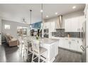 Modern kitchen flows into the living area, featuring white cabinetry, stainless appliances, and a granite island at 6777 Larsh Dr, Denver, CO 80221