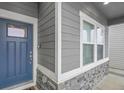 Close-up view of a home's front entrance, highlighting the blue door, stone accents, and modern siding at 239 Chipeta Way, Lochbuie, CO 80603