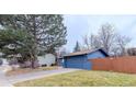 Side view of a blue home with a fenced yard, large tree, and an attached garage at 901 Delphi Dr, Lafayette, CO 80026