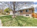 Landscaped front yard of a ranch-style home with brick exterior, mature trees, and a two-car garage at 13367 W Montana Pl, Lakewood, CO 80228