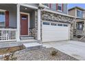 Close-up of a home's exterior showcasing stone accents, a red front door, and a well-maintained front yard at 27425 E Byers Pl, Aurora, CO 80018