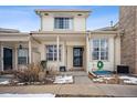 Front view of a light beige townhome with a covered porch and snowy landscaping at 2054 S Xenia Way # 59, Denver, CO 80231