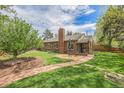 Charming brick home featuring a spacious backyard with a brick patio, beautiful lawn, and mature trees at 1900 Magnolia St, Denver, CO 80220