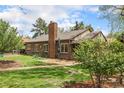 Lovely brick home featuring a spacious backyard with a brick patio, and lush green lawn on a sunny day at 1900 Magnolia St, Denver, CO 80220