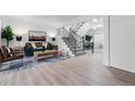 Bright living room features a teal sofa, wood floors, and a black iron staircase at 12054 E 3Rd Ave, Aurora, CO 80011
