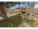 View of a charming two-story home nestled among mature trees and lush landscaping at 1571 S Trenton Ct, Denver, CO 80231
