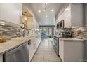 Modern kitchen featuring sleek white cabinetry, stainless steel appliances, and stylish backsplash at 1571 S Trenton Ct, Denver, CO 80231