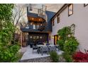 Outdoor patio area featuring a modern seating area, dining table, spiral staircase, and lush landscaping at 2921 Newton St, Denver, CO 80211