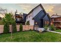 Side view of a modern home featuring a wooden fence, manicured lawn, black siding, and a spiral staircase at 2921 Newton St, Denver, CO 80211