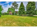 Exterior shot of a well-manicured lawn and lush trees framing the charming brown single-story house at 5722 W Chestnut Ave, Littleton, CO 80128