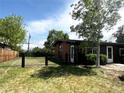 This home features an enclosed yard with a metal fence and mature tree on a sunny day at 5722 W Chestnut Ave, Littleton, CO 80128