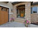 Beautiful stone entryway featuring a wood door with a wreath, potted plants, and a lantern-style light fixture at 14370 Osage St, Westminster, CO 80023