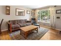 Cozy living room featuring hardwood floors, a comfortable couch, and a large window that allows natural light to flood the space at 14050 E 25Th Pl, Aurora, CO 80011